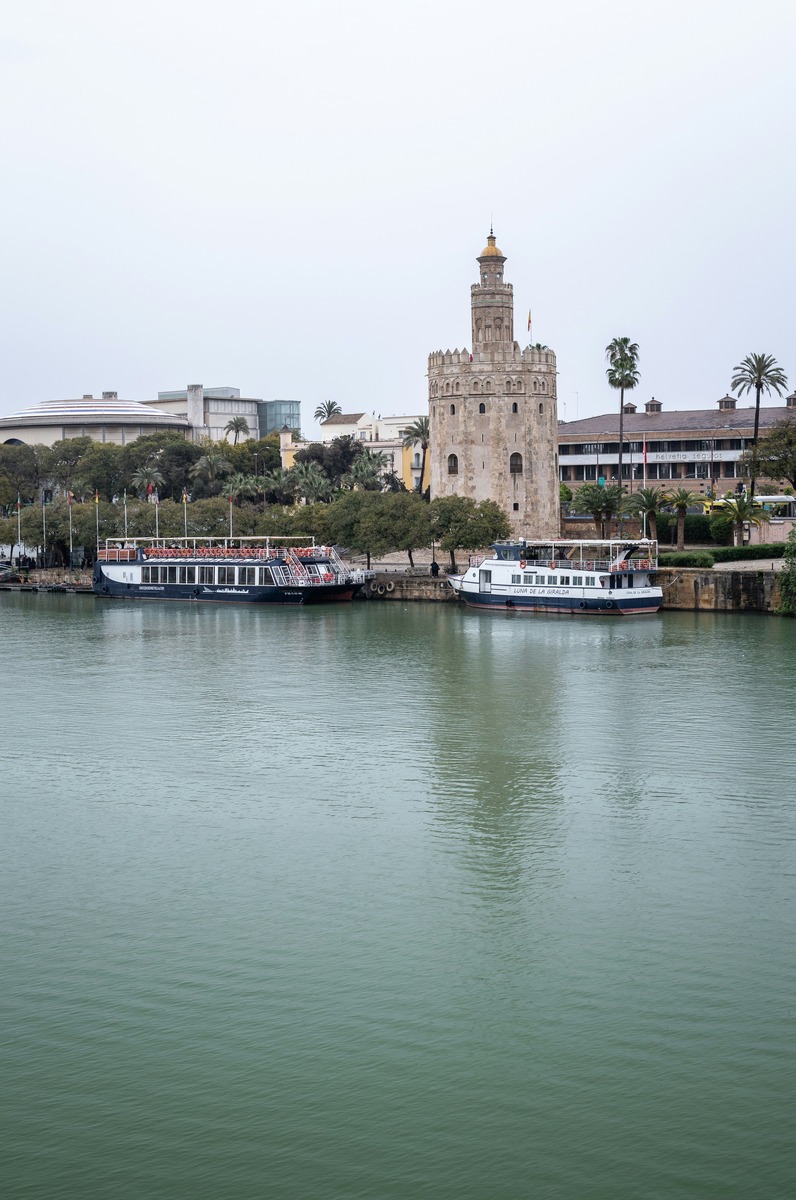 El cauce del Guadalquivir y los barcos de paseo frente a la Torre del Oro en una jornada de cielo cubierto