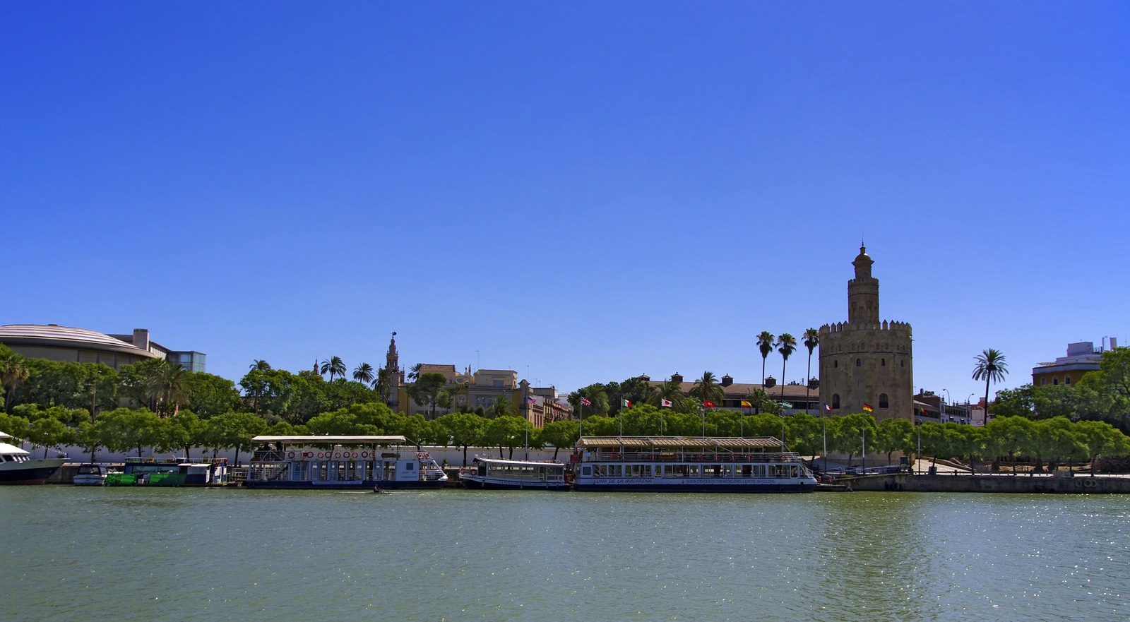 Panorámica horizontal del río Guadalquivir con la hilera de barcos y la Torre del Oro