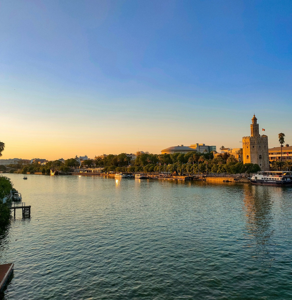Reflejos del atardecer en el agua del Guadalquivir con la Torre del Oro y la arboleda del paseo