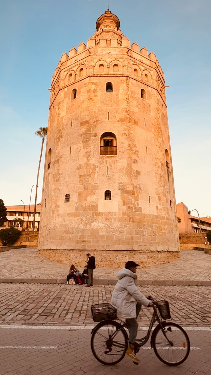 Un ciclista pasa frente a la base de la Torre del Oro por el carril bici