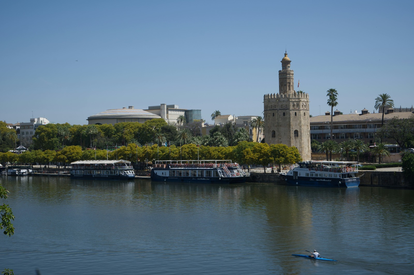 Vista de la Torre del Oro desde el río Guadalquivir con los barcos turísticos atracados frente al monumento