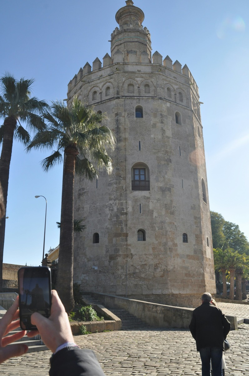 Un turista fotografía la Torre del Oro con su teléfono móvil desde el paseo