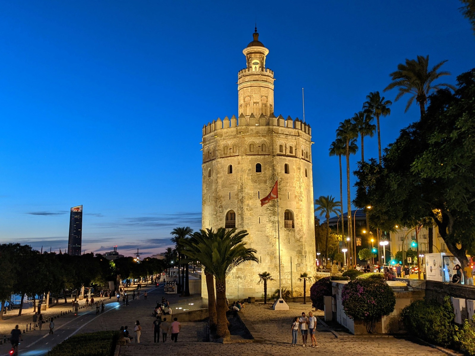 Escena nocturna de la Torre del Oro iluminada junto al paseo del río