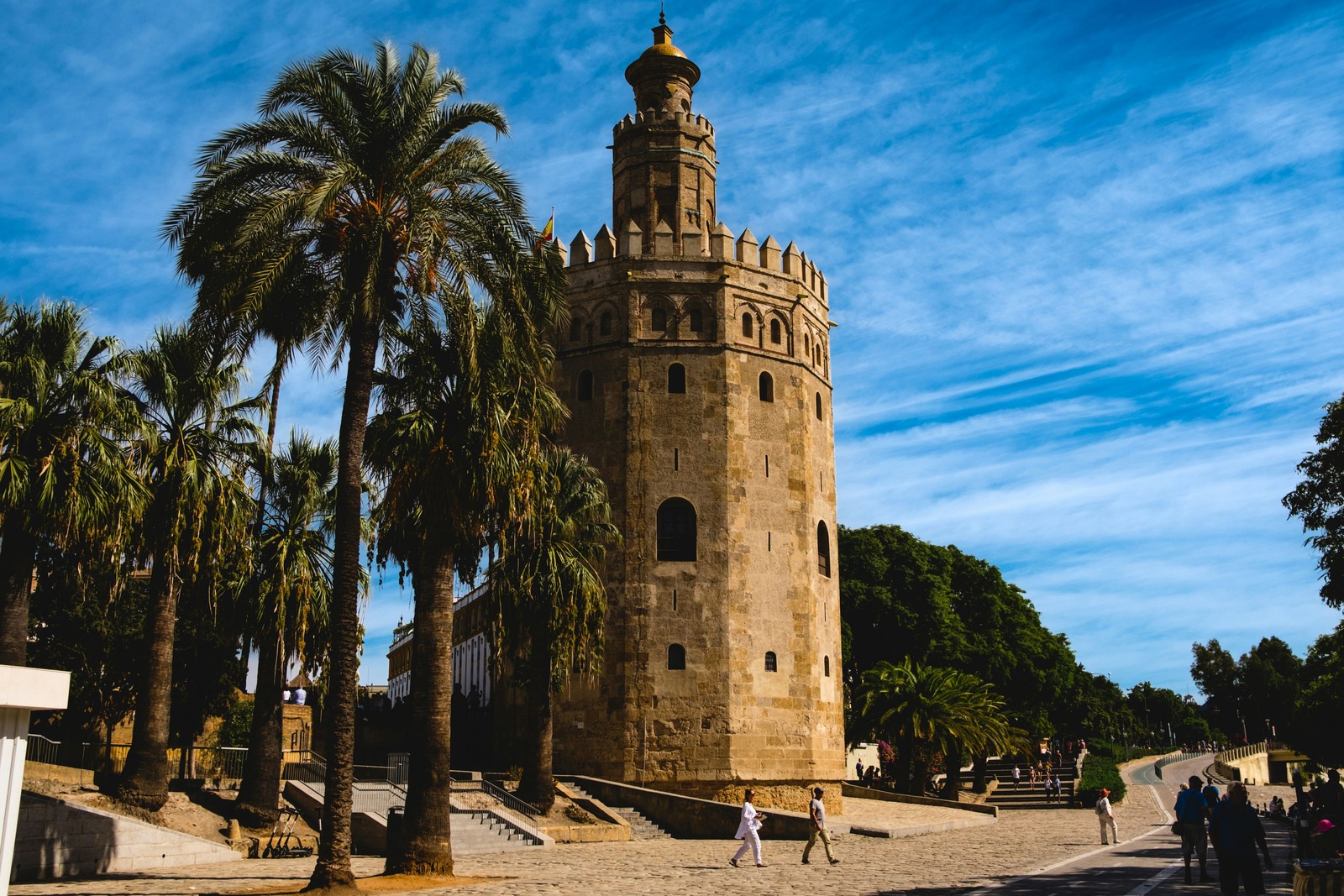 La base de la Torre del Oro con transeúntes paseando por la zona empedrada